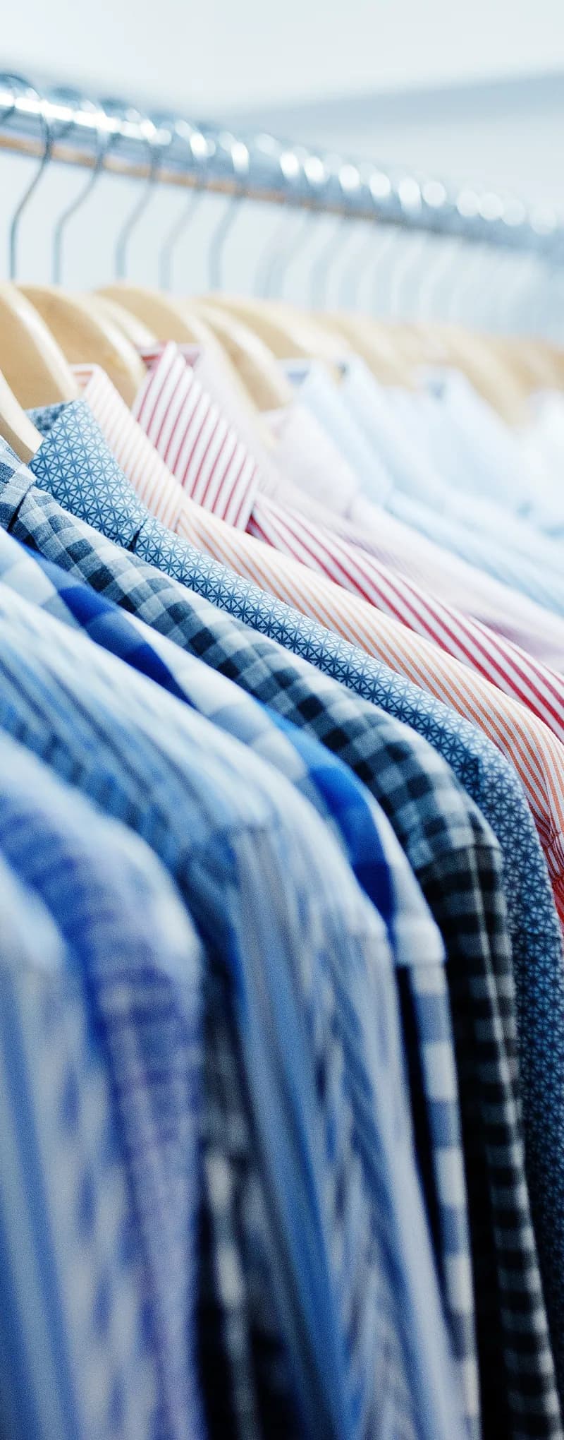 Pressed shirts hanging in a row on wooden hangers