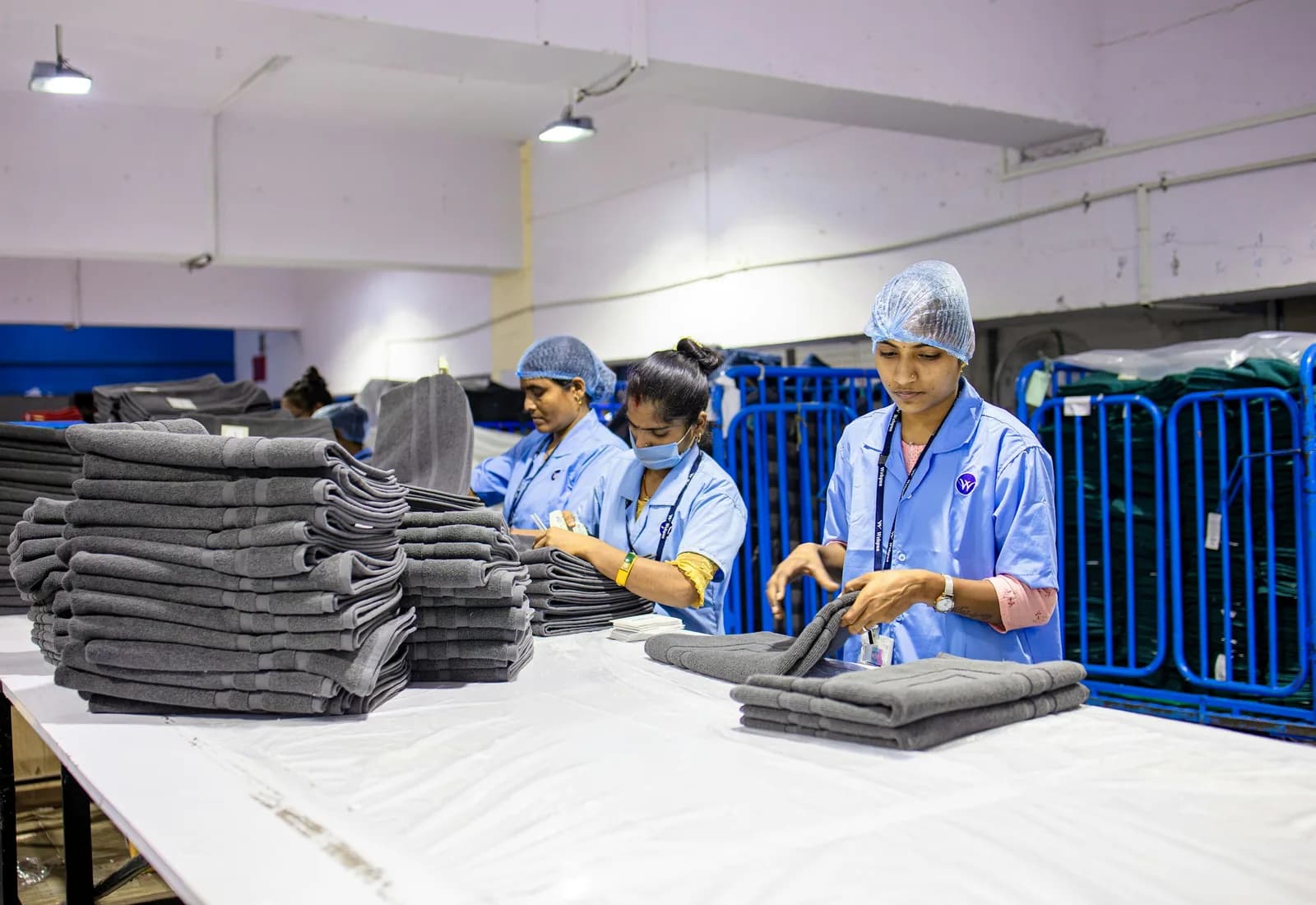 Staff folding and stacking freshly cleaned laundry at a long table