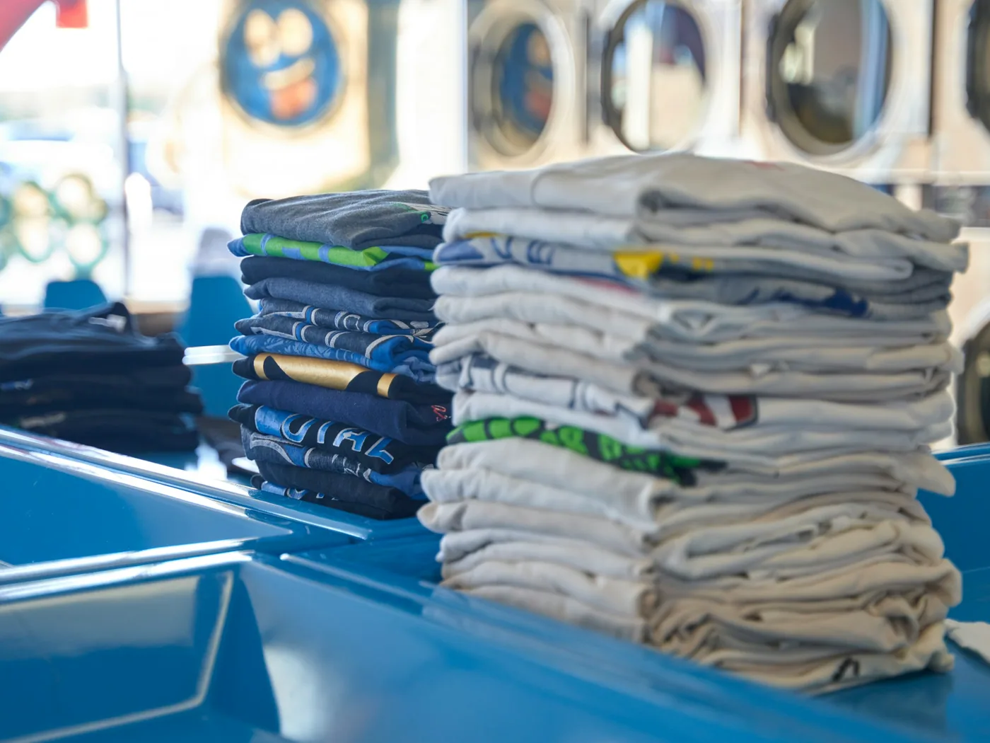 Folded clothes stacked on a counter inside a laundry